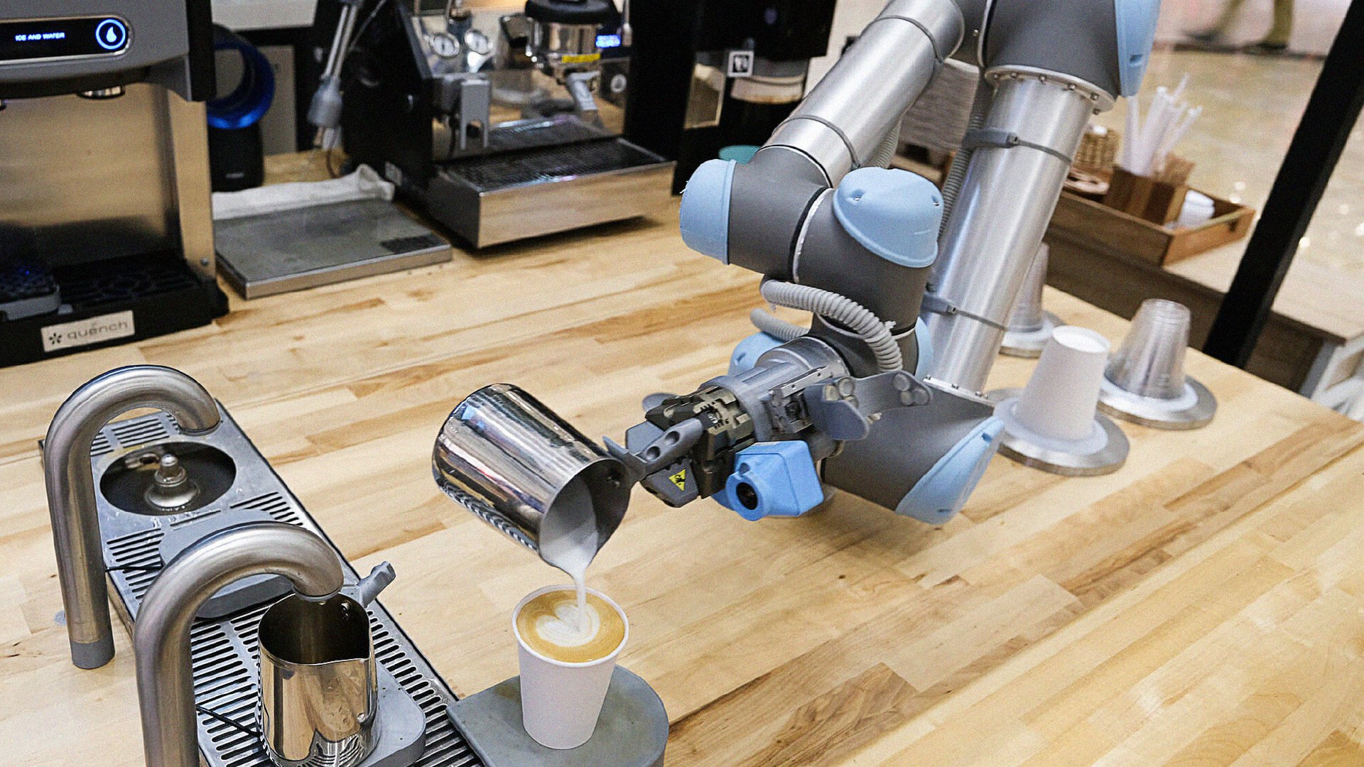 A robot arm pours freshly steamed milk into a cup creating latte art