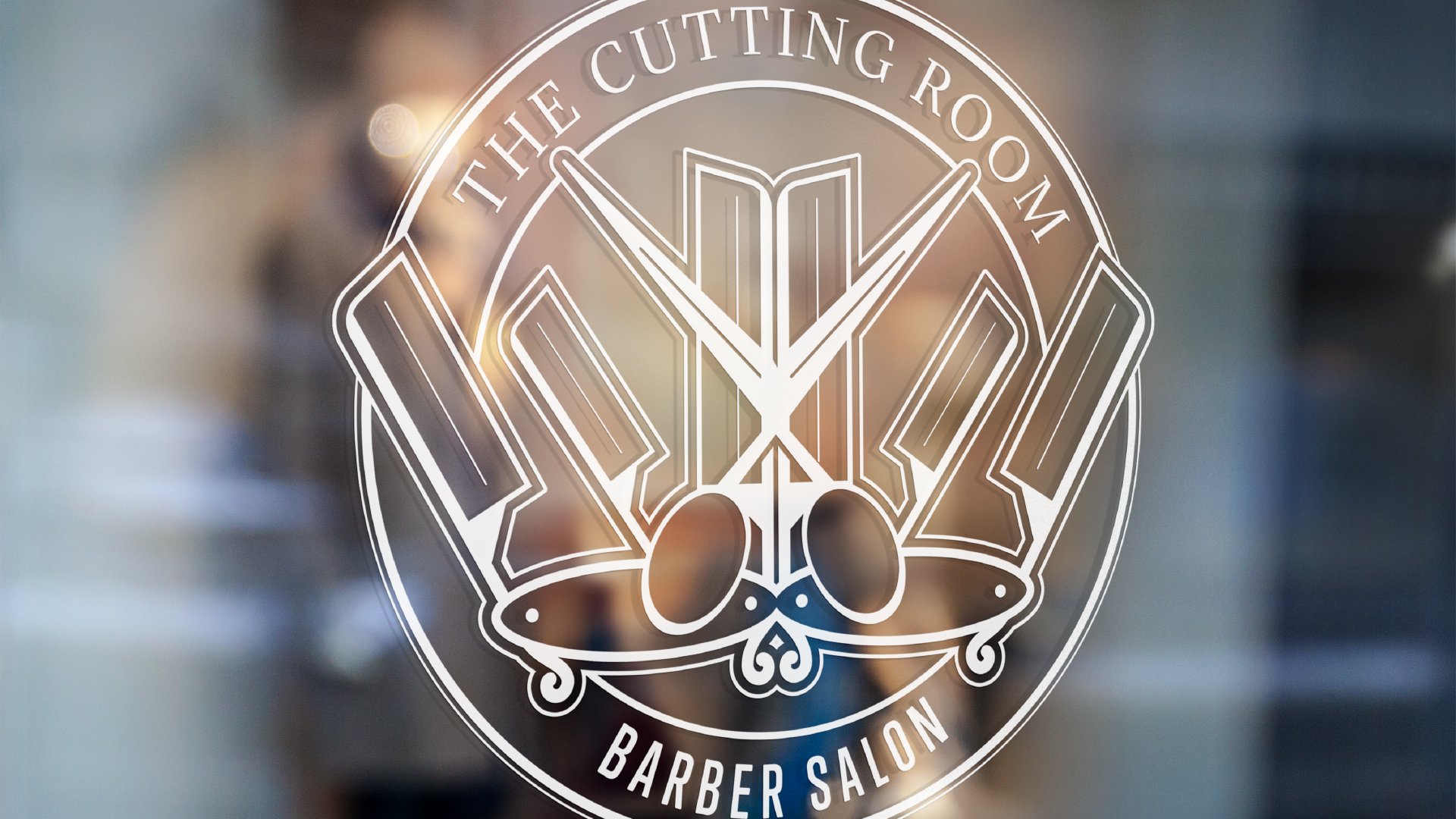 The Cutting Room Barber Salon logo is on a glass door. The words circle round a series of six shaving blades pointed to the middle and a pair of scissors in the center.