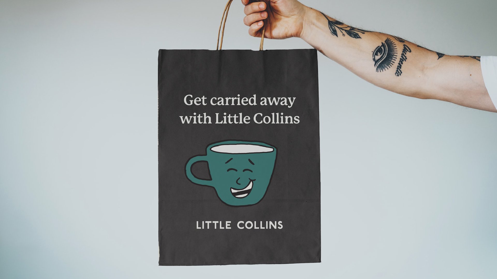 A tattooed arm holds a Little Collins bag. The text says, “Get carried away with Little Collins,” and features a mug illustration with a laughing face.