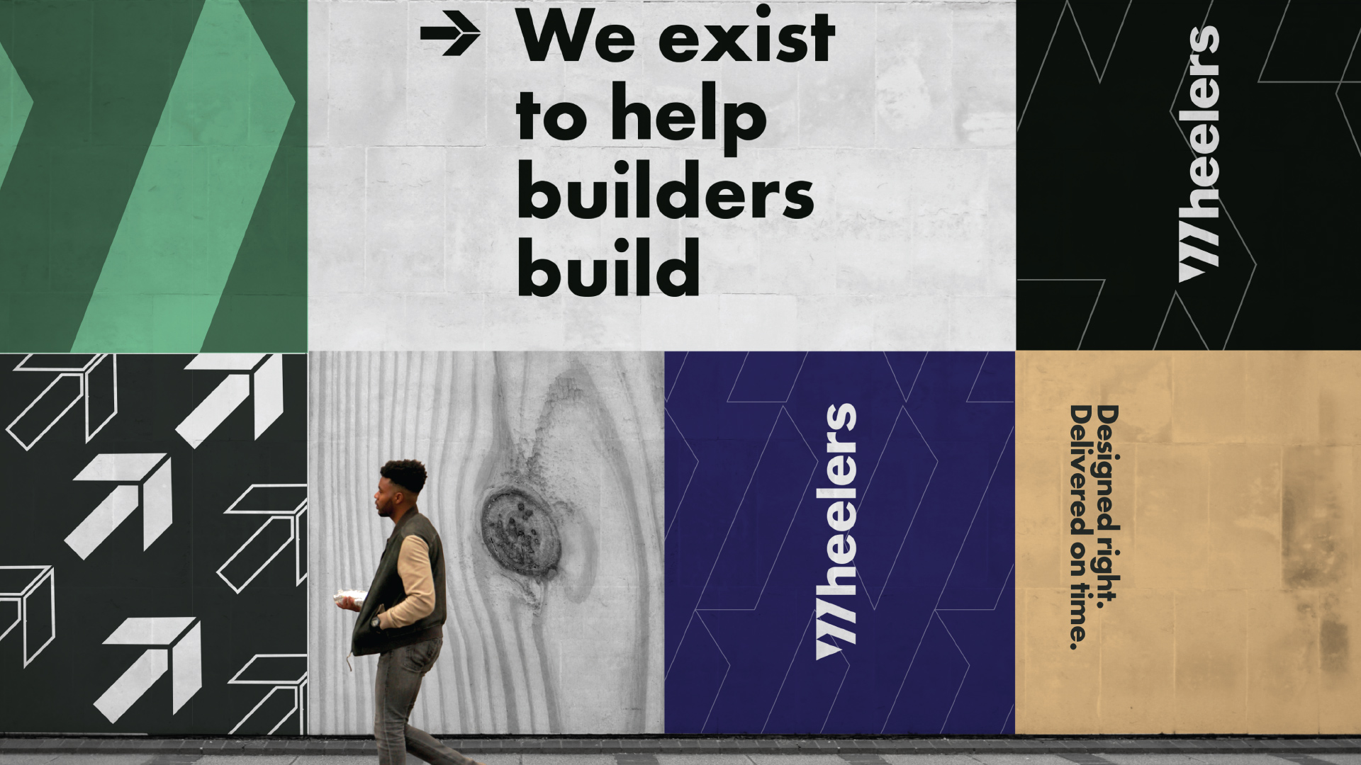 A man walks past a wall of a series of Wheelers images. It features the watermark, the wood grain, and arrows that mimic the peak of a truss. Text includes the phrases, “We exist to help builders build” and “Designed right. Delivered on time.”